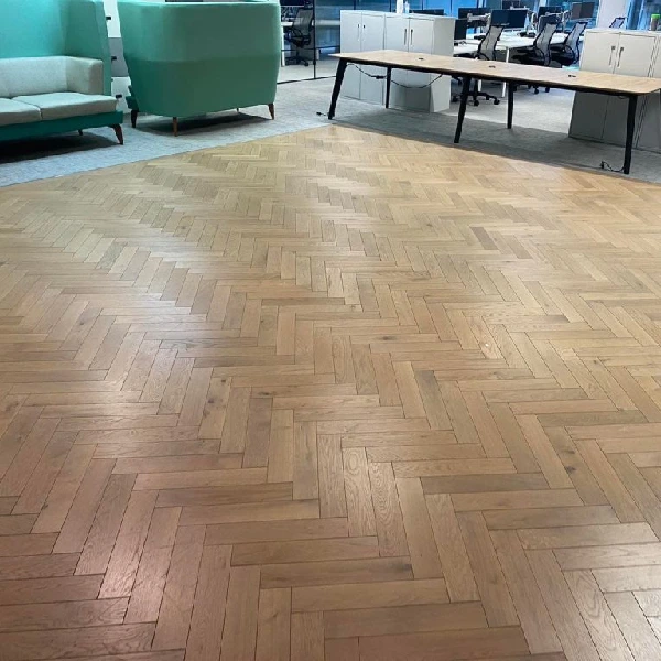 Sanding a light wood herringbone floor in a modern office