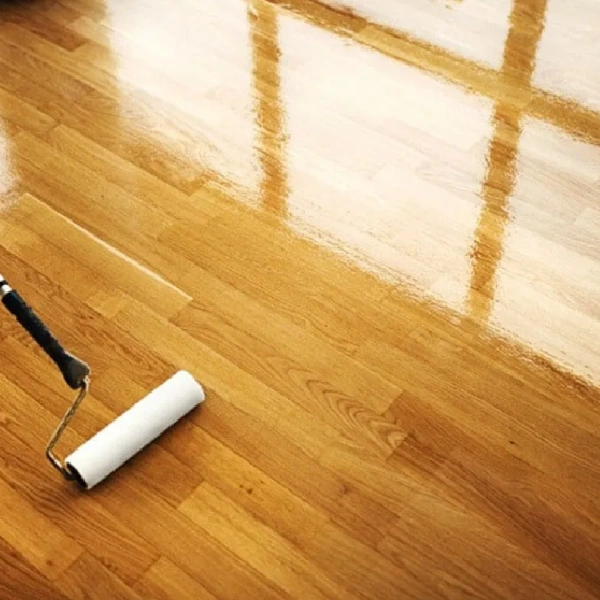 paint roller applying a protective hardwax oil finish to a hardwood floor