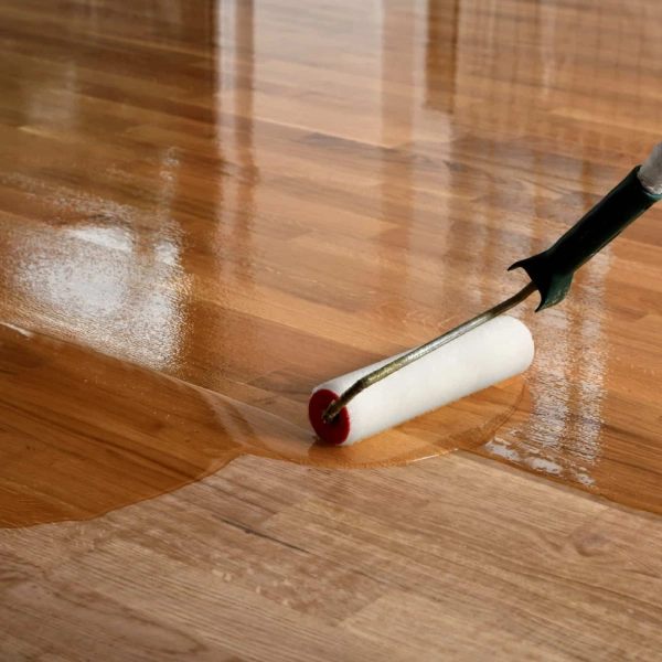 worker applying an oil-based polyurethane finish to hardwood floors